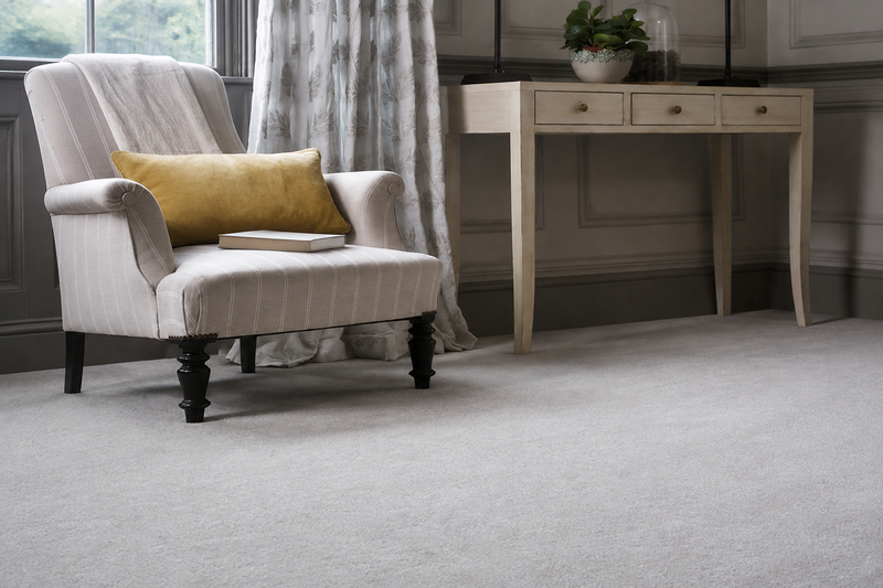Quiet reading corner with soft grey fitted carpet, a striped armchair and mustard cushion.